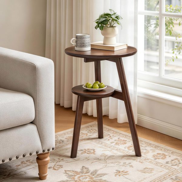 2-tier round side table in walnut finish beside a sunny window, holding a mug and a potted plant