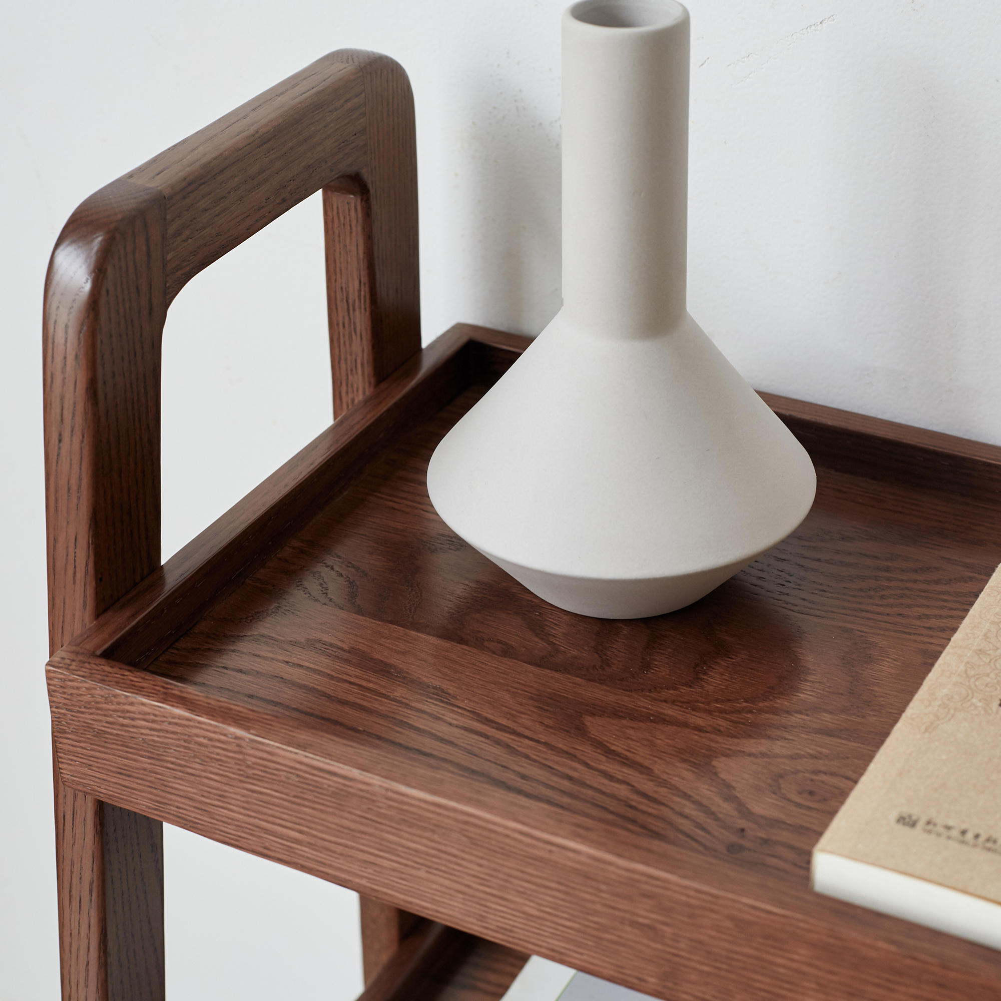 Walnut finish ladder shelf top tray with a white vase