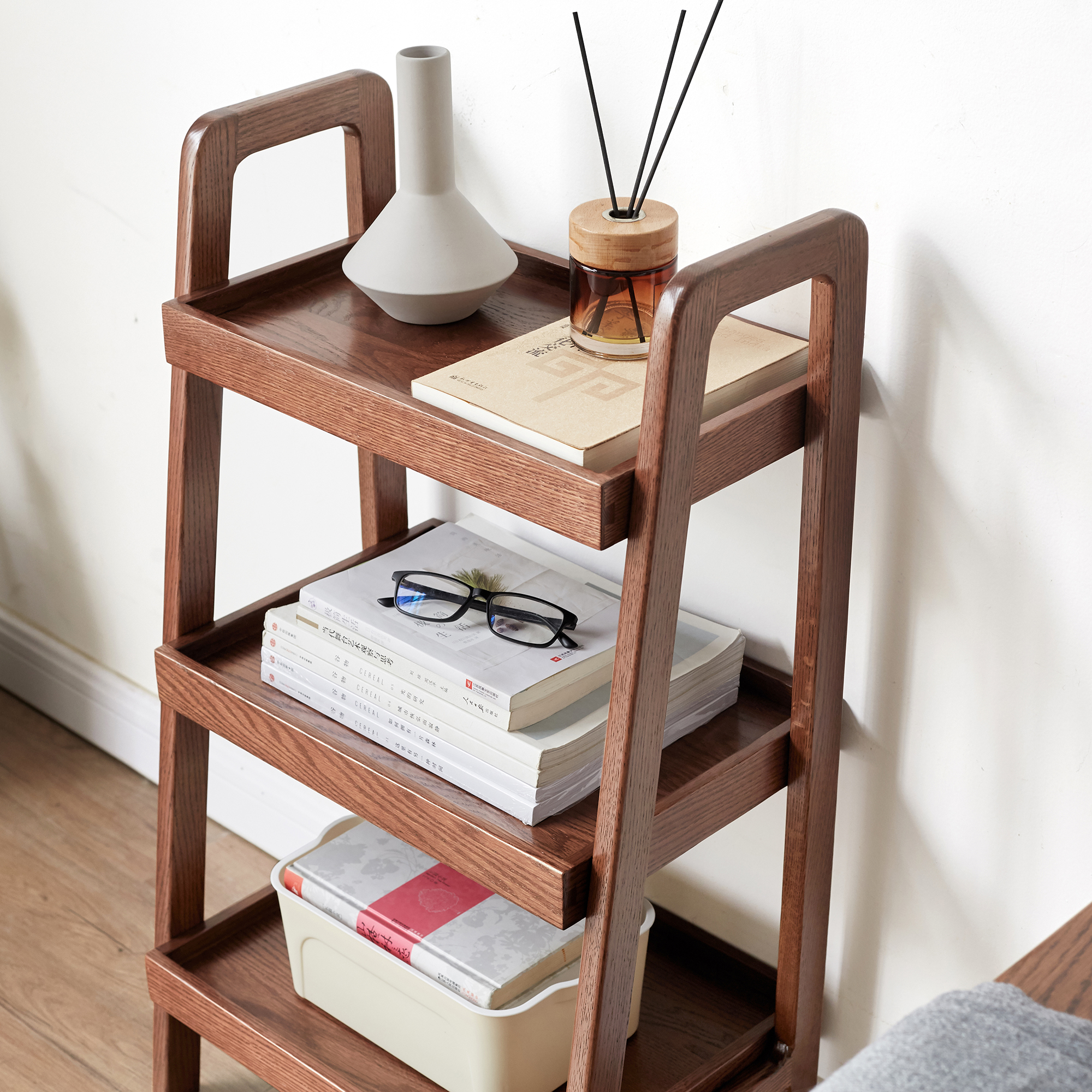 Walnut finish oak ladder shelf styled with books and reed diffuser