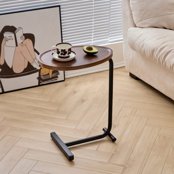 C-shaped sofa table slid over the arm of a beige couch in a bright living room
