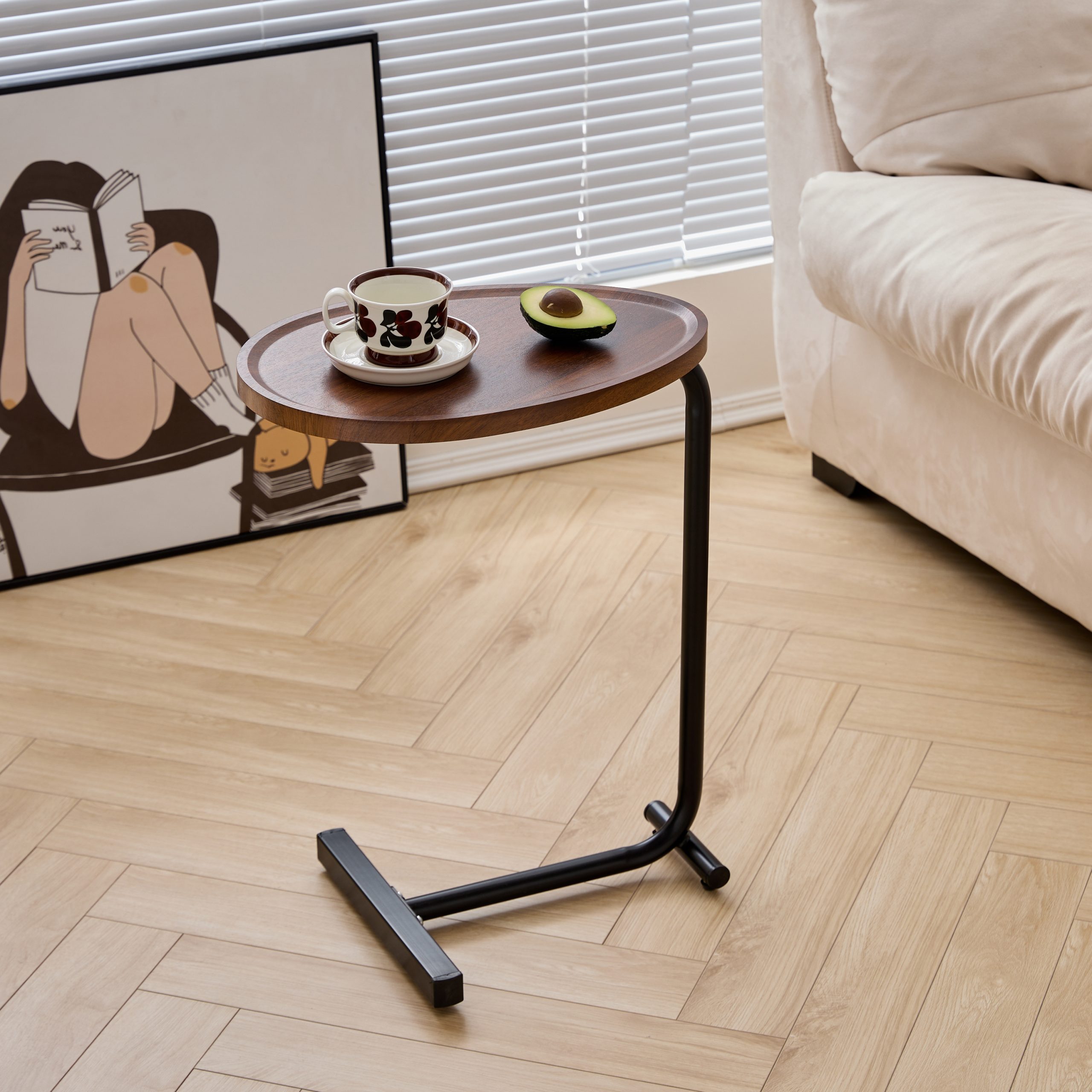 C-shaped sofa table slid over the arm of a beige couch in a bright living room