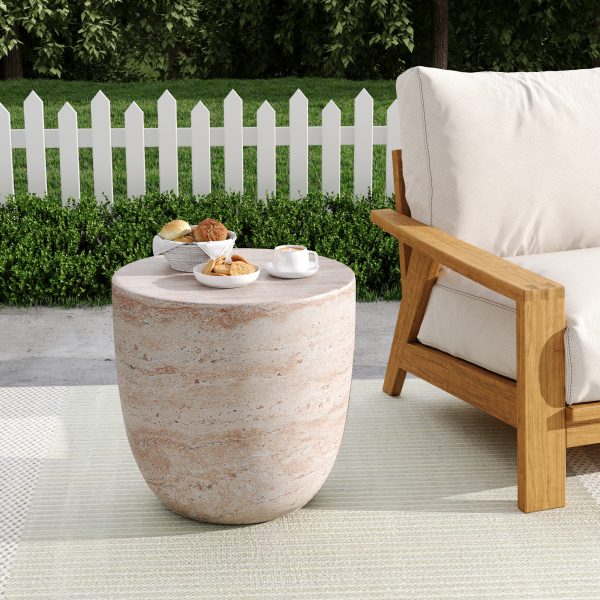 Travertine barrel side table holding a drink beside outdoor lounge chairs on a patio