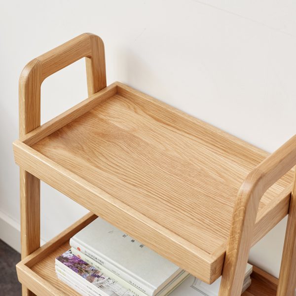 Raised edge top tray of the oak ladder shelf holding a vase