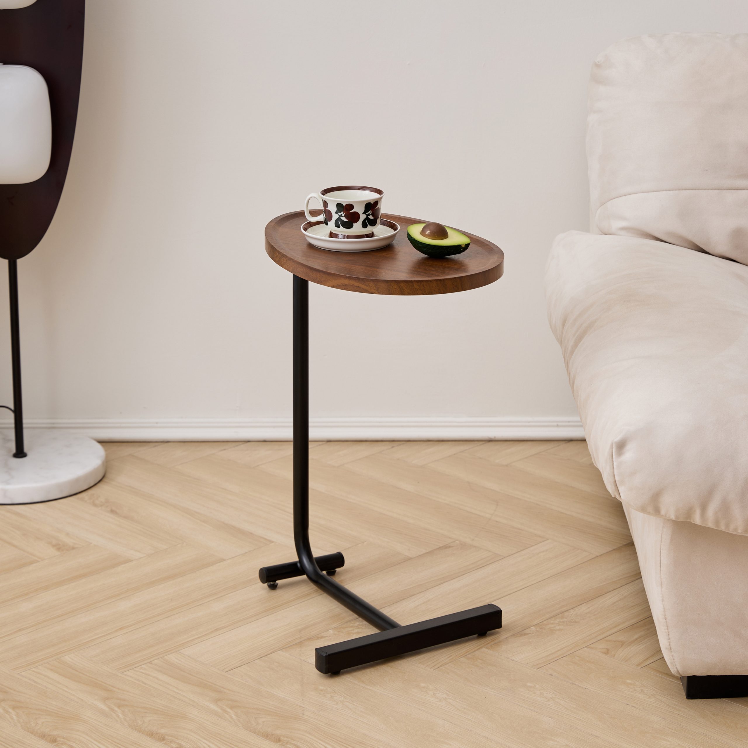 C-shaped side table with walnut top and black steel base in a bright living room with herringbone floor